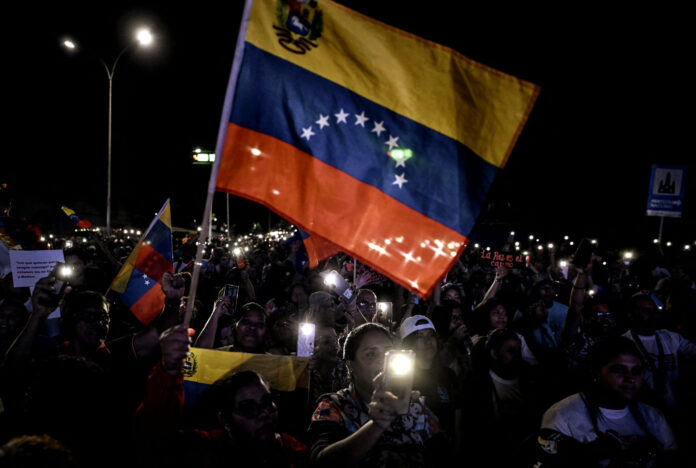 Apoiadores do presidente da Venezuela, Nicolás Maduro, agitam uma bandeira venezuelana durante um ato em defesa da paz em Caracas