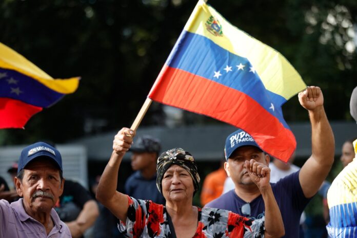 Apoiadores do presidente venezuelano Nicolás Maduro exibem bandeiras da Venezuela após sequestro do mandatário pelos Estados Unidos.