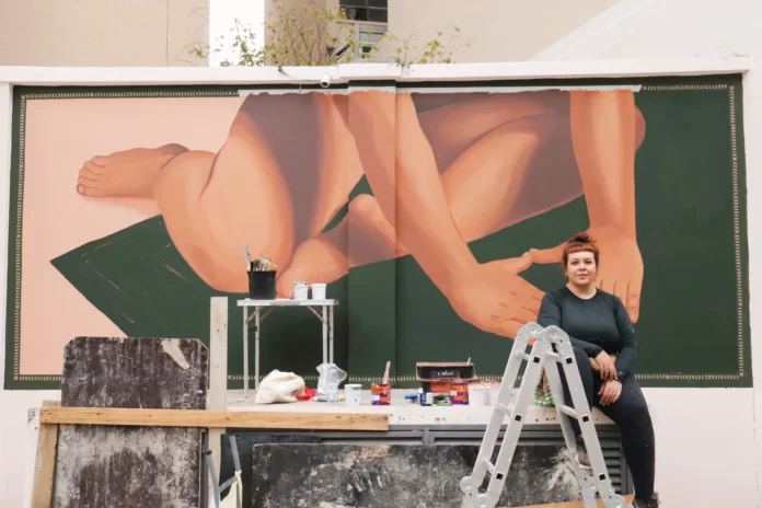 Priscila Barbosa em frente ao mural desenhado e pintado por ela no edifício Elza Soares, no centro de São Paulo